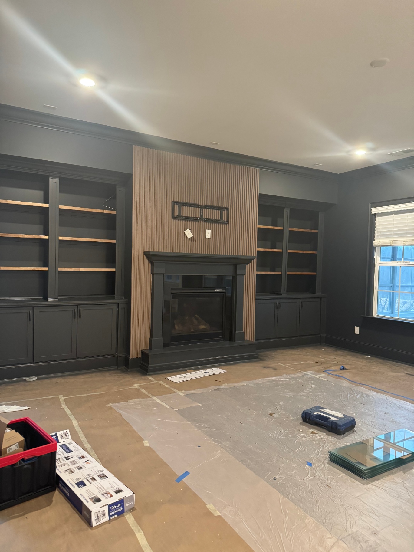 Custom built-in shelves and fireplace in deep charcoal with fluted wood accent